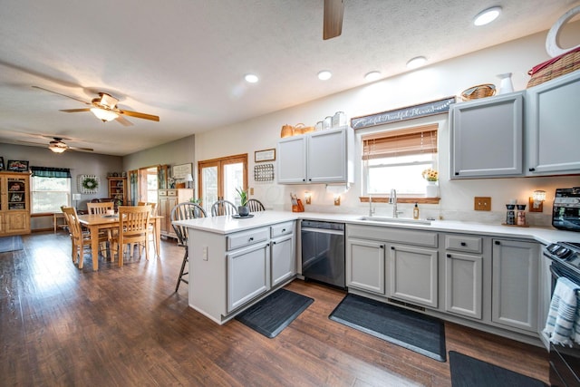 kitchen featuring light countertops, a sink, a peninsula, and stainless steel dishwasher