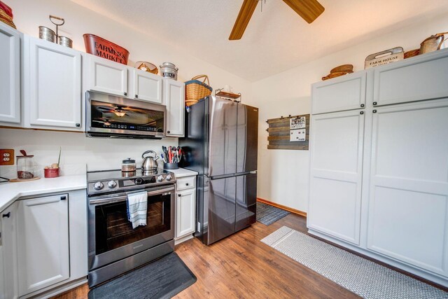 kitchen with stainless steel appliances, light countertops, white cabinetry, and light wood-style floors