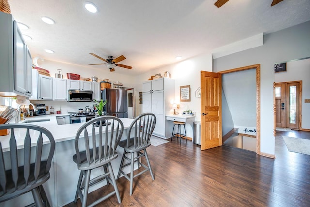 kitchen with white cabinetry, appliances with stainless steel finishes, light countertops, and dark wood finished floors