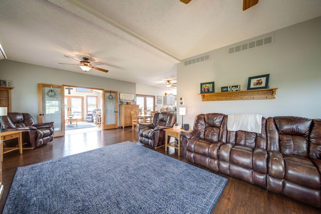 living room with a ceiling fan, visible vents, dark wood finished floors, and a textured ceiling