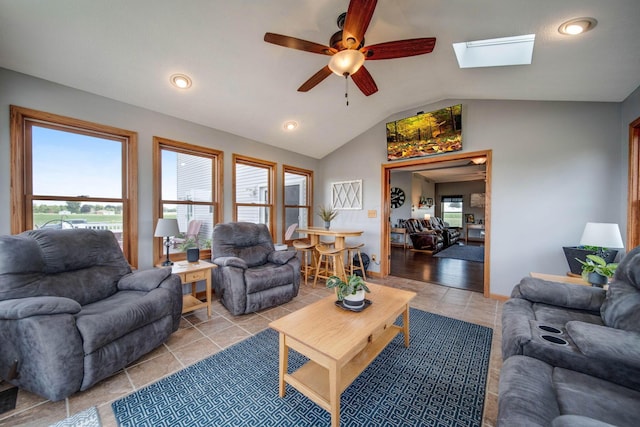 living room with vaulted ceiling with skylight, a healthy amount of sunlight, and light tile patterned floors