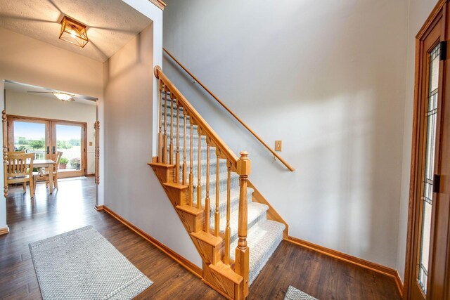 staircase with french doors, wood finished floors, and baseboards