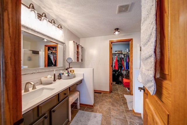 bathroom featuring visible vents, tile patterned flooring, walk in shower, a textured ceiling, and vanity