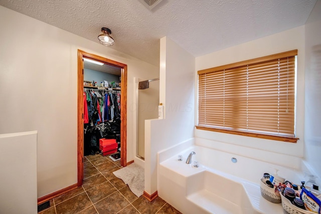 bathroom with a walk in closet, a garden tub, a shower stall, a textured ceiling, and baseboards