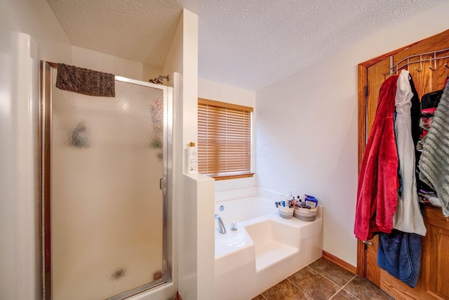 full bathroom featuring a garden tub, a textured ceiling, a shower stall, and tile patterned floors