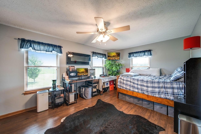 bedroom with a ceiling fan, a textured ceiling, baseboards, and wood finished floors