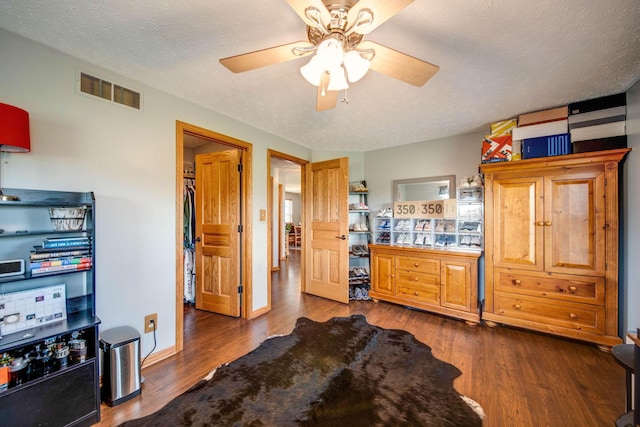 interior space featuring baseboards, visible vents, dark wood finished floors, ceiling fan, and a textured ceiling