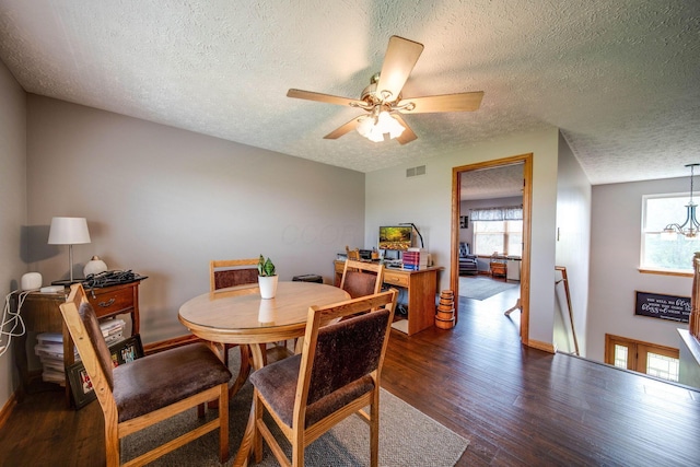 dining space featuring baseboards, visible vents, dark wood-type flooring, a textured ceiling, and ceiling fan with notable chandelier