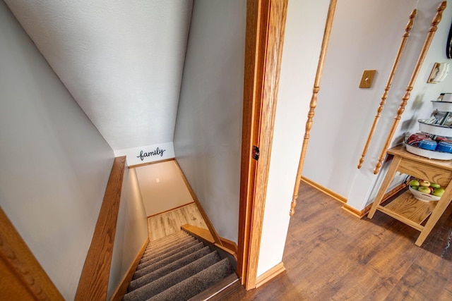 staircase featuring lofted ceiling, baseboards, and wood finished floors