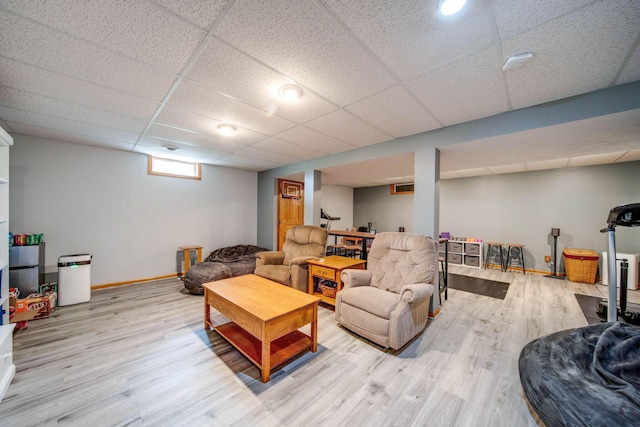 living area featuring a drop ceiling, baseboards, and wood finished floors