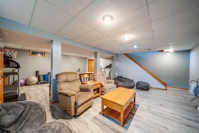 living room featuring a paneled ceiling, baseboards, and wood finished floors