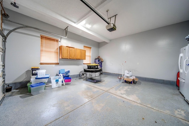 garage featuring a garage door opener, freestanding refrigerator, and baseboards