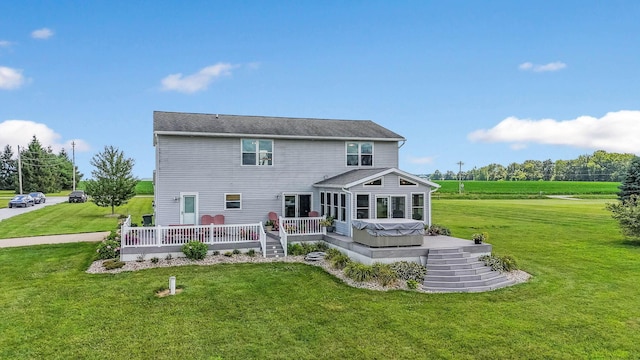 rear view of property with a yard, a hot tub, a sunroom, and a wooden deck