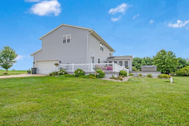 rear view of property featuring a yard, driveway, and an attached garage