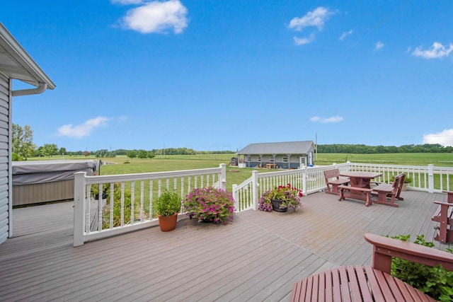 wooden deck with a rural view, a lawn, and a hot tub