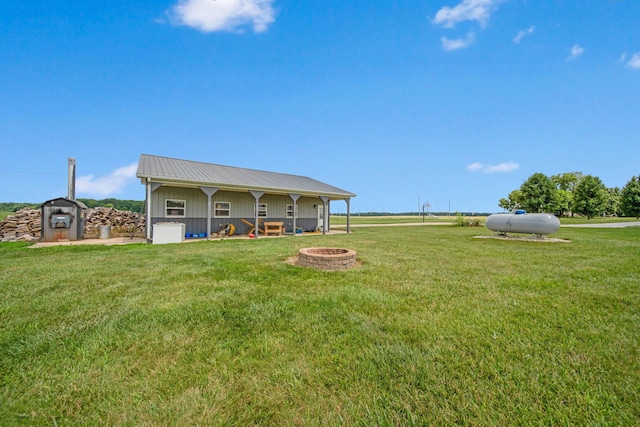 rear view of property featuring a fire pit, metal roof, and a lawn