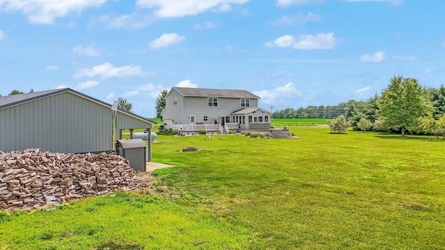 back of property with a fire pit, a lawn, and a wooden deck