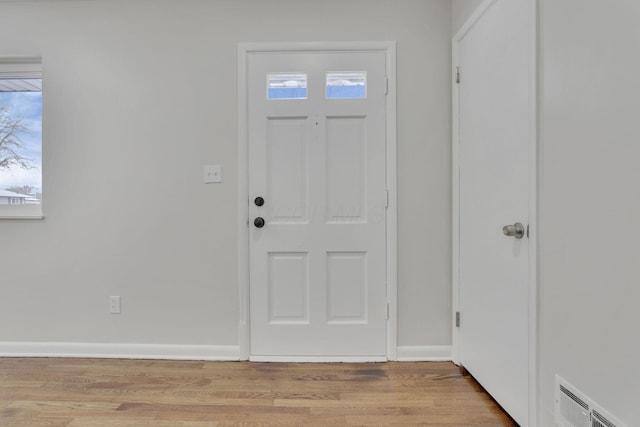 foyer with light wood-style flooring, visible vents, and baseboards