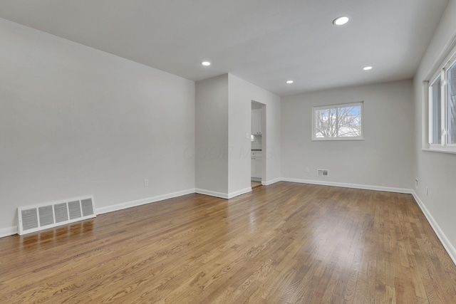 unfurnished room with light wood finished floors, recessed lighting, visible vents, and baseboards