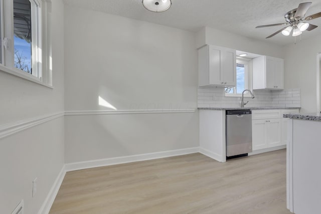 kitchen with light wood-style flooring, white cabinetry, baseboards, backsplash, and dishwasher