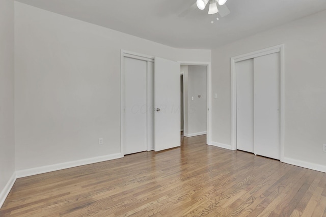 unfurnished bedroom with baseboards, ceiling fan, light wood-style floors, and multiple closets