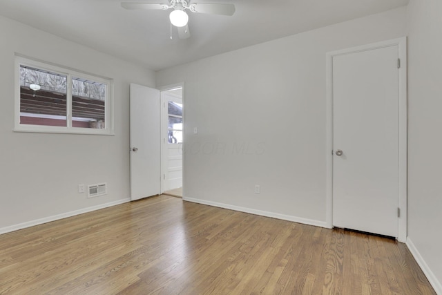 empty room with baseboards, visible vents, ceiling fan, and light wood finished floors