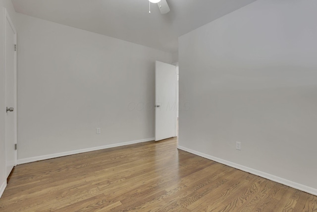 spare room featuring light wood finished floors, ceiling fan, and baseboards