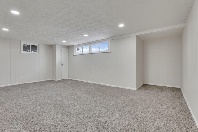 below grade area with a textured ceiling, baseboards, carpet flooring, and recessed lighting