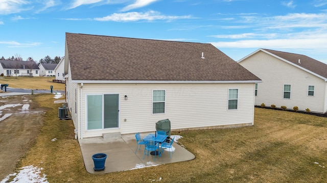 back of house with a shingled roof, a patio, a lawn, and central air condition unit