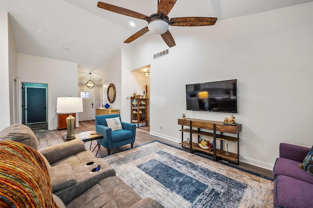 living area with baseboards, high vaulted ceiling, visible vents, and light wood-style floors