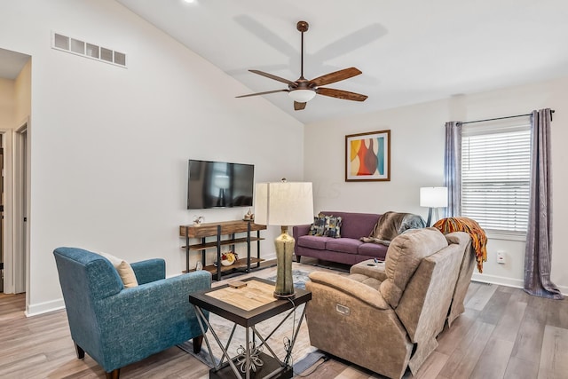 living area featuring light wood finished floors, baseboards, visible vents, a ceiling fan, and vaulted ceiling