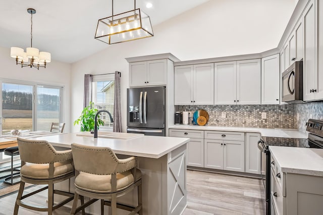 kitchen featuring black appliances, light countertops, a kitchen island with sink, and decorative light fixtures