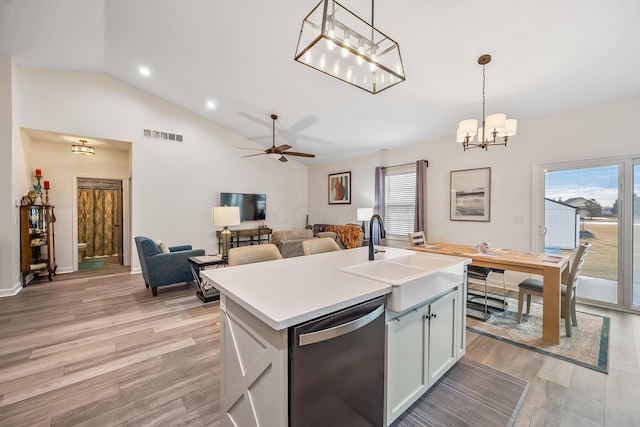 kitchen featuring decorative light fixtures, light countertops, a sink, an island with sink, and dishwasher