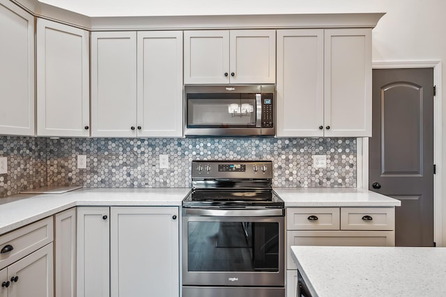 kitchen featuring stainless steel appliances, light stone counters, and backsplash