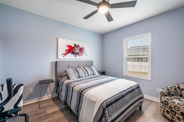 bedroom with ceiling fan, baseboards, and wood finished floors