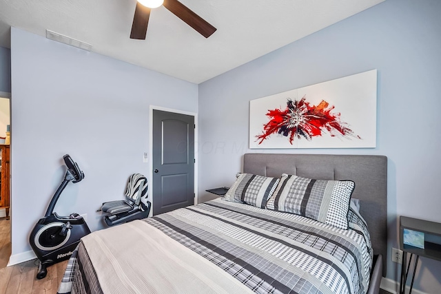 bedroom featuring baseboards, ceiling fan, visible vents, and wood finished floors