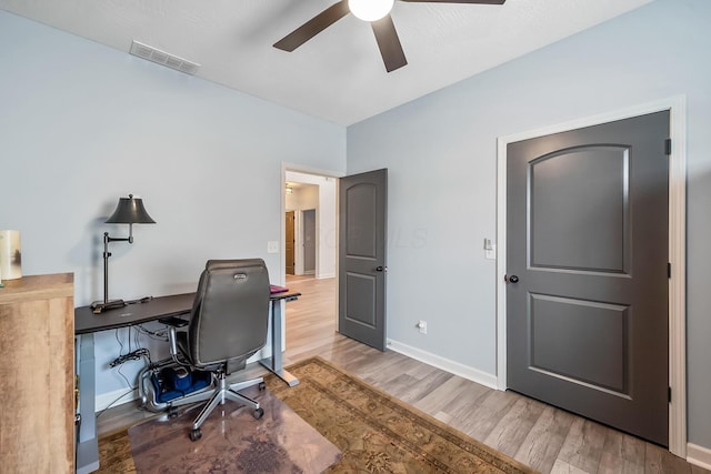 office space with a ceiling fan, baseboards, visible vents, and wood finished floors