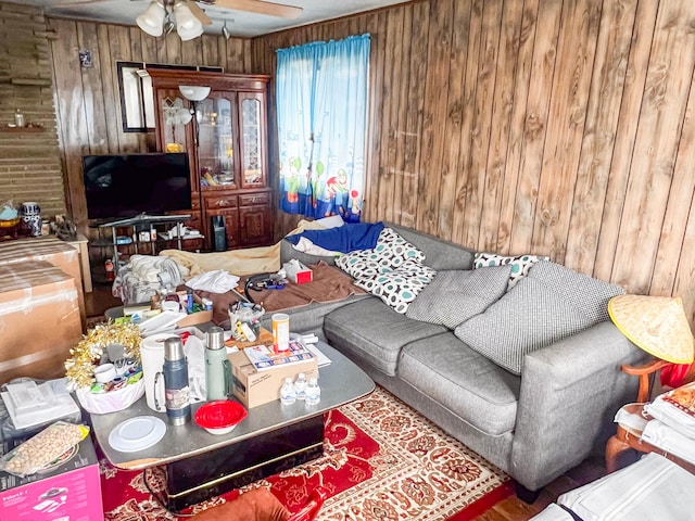 living area with wood walls and a ceiling fan