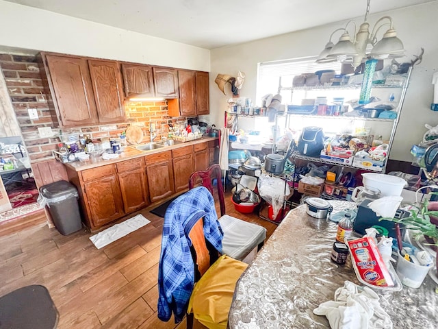 kitchen with a sink, light countertops, brown cabinets, light wood finished floors, and decorative light fixtures