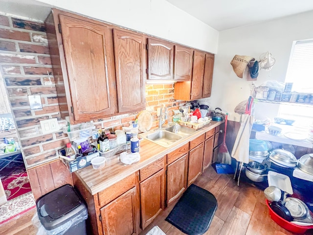 kitchen with brown cabinetry, dark wood-style flooring, light countertops, and a sink