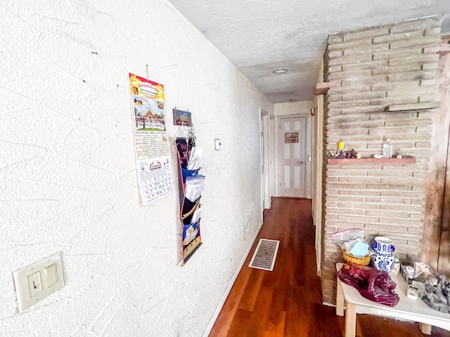 hall featuring visible vents, a textured ceiling, and wood finished floors