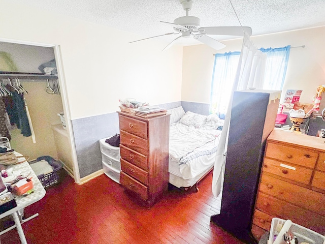 bedroom with a closet, a textured ceiling, a ceiling fan, and dark wood-type flooring