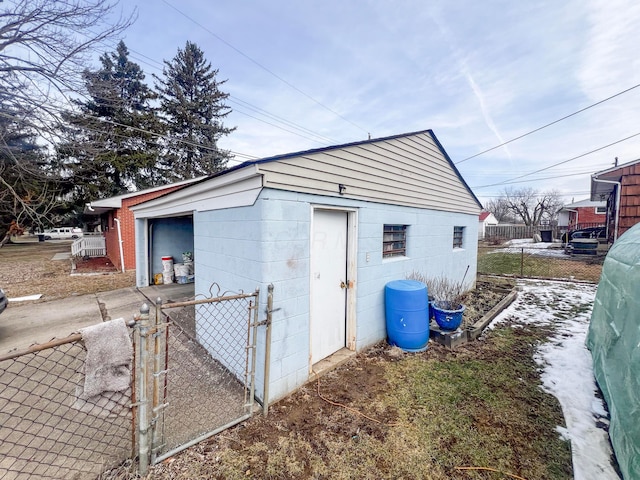 view of outdoor structure featuring concrete driveway and fence