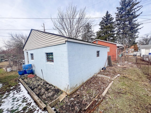 view of property exterior with concrete block siding and fence