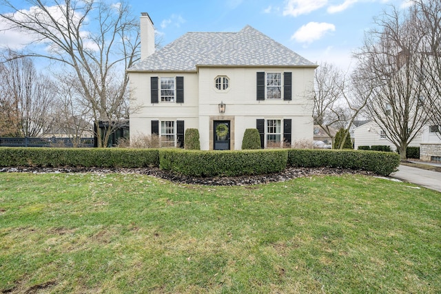 french country inspired facade featuring a chimney and a front yard