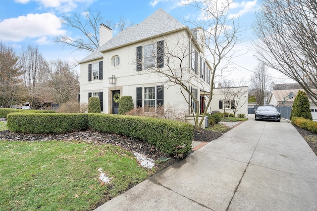 view of front of home featuring stucco siding, a chimney, and a front yard