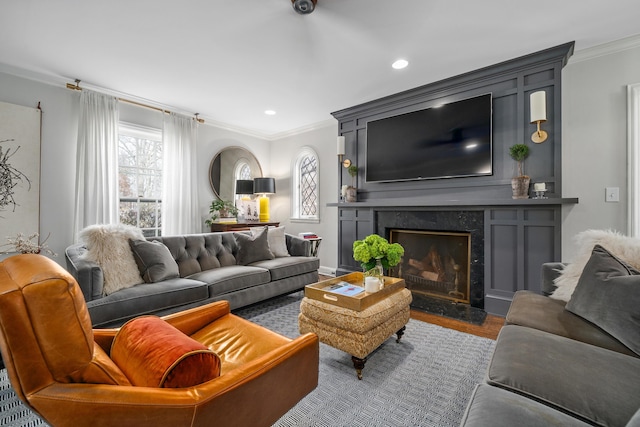 living room with ornamental molding, wood finished floors, a high end fireplace, and recessed lighting