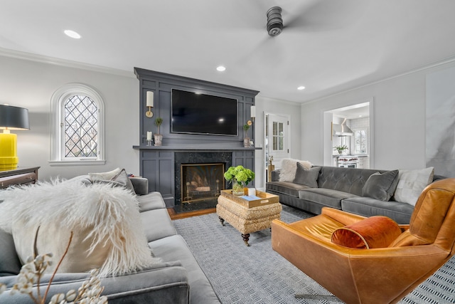 living room featuring recessed lighting, a fireplace, crown molding, and wood finished floors