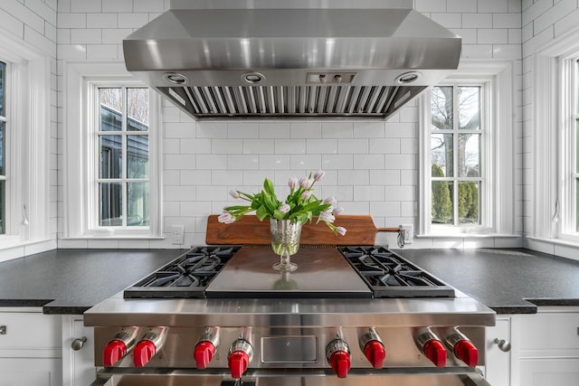 kitchen featuring stove, white cabinetry, ventilation hood, tasteful backsplash, and dark countertops