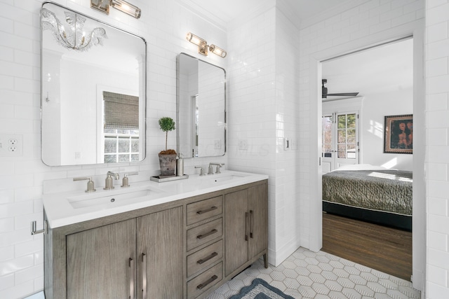 full bathroom featuring crown molding, a sink, tile walls, and ensuite bath